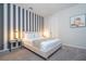 Stylish bedroom featuring a queen bed with striped accent wall, gray carpet, and modern furniture at 9038 Sunshine Ridge Loop, Kissimmee, FL 34747