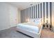 Stylish bedroom featuring a queen bed with striped accent wall, gray carpet, and modern furniture at 9038 Sunshine Ridge Loop, Kissimmee, FL 34747