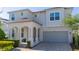 Charming two-story home featuring an inviting front porch with columns and a paved driveway to a two-car garage at 9038 Sunshine Ridge Loop, Kissimmee, FL 34747