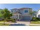 Beautiful two-story home with a welcoming columned porch, a paved driveway, and a two-car garage at 9038 Sunshine Ridge Loop, Kissimmee, FL 34747