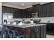 Modern kitchen features stainless steel appliances, granite countertops, island with seating and stylish, dark cabinets at 9038 Sunshine Ridge Loop, Kissimmee, FL 34747