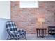 Upstairs living room with brick accent wall, reading chair, table with lamp and plenty of natural light at 9038 Sunshine Ridge Loop, Kissimmee, FL 34747
