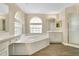 Bright bathroom featuring a soaking tub, arched windows, and white cabinets at 922 Hatteras Ave, Minneola, FL 34715