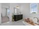 Bright bathroom featuring a soaking tub with brass fixtures, a dark wood vanity and natural light at 1071 Kershaw Dr, Winter Garden, FL 34787