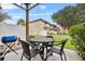 Outdoor patio with a round table, chairs, grill, and green lawn at 1084 Park Ridge Cir, Kissimmee, FL 34746