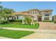 Inviting two-story home featuring lush landscaping, a terracotta tile roof, and a brick paved driveway at 13125 Alderley Dr, Orlando, FL 32832