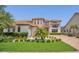 Elegant two-story home with landscaped front yard, paver driveway, and a decorative wrought iron balcony at 13125 Alderley Dr, Orlando, FL 32832