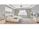 Spacious primary bedroom with neutral gray tones, a cushioned bench, and tray ceiling at 13125 Alderley Dr, Orlando, FL 32832