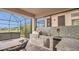 Outdoor kitchen with a built-in grill, sink, and stainless steel storage, leading to a hot tub at 13125 Alderley Dr, Orlando, FL 32832