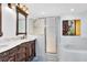 A bathroom featuring a double sink vanity with a decorative dark wood cabinet and a glass enclosed shower and bathtub at 14883 Hartford Run Dr, Orlando, FL 32828