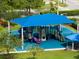 Community playground with blue shade structure, slides, climbing structure and benches at 14883 Hartford Run Dr, Orlando, FL 32828