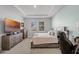 Carpeted bedroom with a bed, nightstands, and a large TV with two windows letting in natural light at 14925 Lebeau Loop, Winter Garden, FL 34787