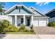 Charming two-story home with blue accents, a welcoming front porch, and a brick driveway leading to a two-car garage at 14925 Lebeau Loop, Winter Garden, FL 34787