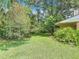 Lush backyard featuring mature trees, blooming pink flowers and a healthy green lawn with landscaping at 1591 Revere Ln, Daytona Beach, FL 32117