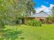 Spacious backyard with lush green grass, mature trees, and partial brick exterior at 1591 Revere Ln, Daytona Beach, FL 32117