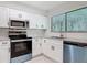 Bright kitchen with stainless steel appliances, granite countertops, and sleek white cabinetry at 1591 Revere Ln, Daytona Beach, FL 32117