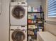 Convenient laundry room featuring stacked washer and dryer with shelving for storage and folding space at 1791 Spruce Ave, Winter Park, FL 32789