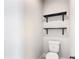 Bright half bath with a toilet and floating black shelves for decorative storage, offering convenient functionality at 2943 Slough Creek Dr, Kissimmee, FL 34744