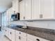 Well-lit kitchen featuring granite countertops, white cabinets, and modern stainless steel appliances at 2943 Slough Creek Dr, Kissimmee, FL 34744