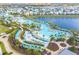 Aerial view of the community pool, a lake, walking paths, and colorful residential buildings at 3036 Parrot Head Pl, Kissimmee, FL 34747
