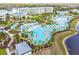Aerial view of the resort-style pool area with palm trees, cabanas, lounge chairs, and a lake at 3036 Parrot Head Pl, Kissimmee, FL 34747