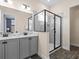 Elegant bathroom with double vanity, modern sinks, gray cabinetry, and glass-enclosed shower at 3036 Parrot Head Pl, Kissimmee, FL 34747