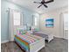 Bright bedroom featuring two twin beds with colorful striped bedding, ceiling fan, and cool blue walls at 3036 Parrot Head Pl, Kissimmee, FL 34747