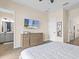 Bright bedroom featuring wood-look tile flooring, wall-mounted TV, and access to the ensuite bathroom at 3036 Parrot Head Pl, Kissimmee, FL 34747