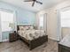Bedroom with a queen bed and palm tree bedding and accents, two windows, and wood-look tile flooring at 3036 Parrot Head Pl, Kissimmee, FL 34747