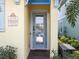 Close up shot of the front door of a beach-themed yellow house featuring a glass door with an entrance sign at 3036 Parrot Head Pl, Kissimmee, FL 34747