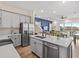 Spacious kitchen with stainless appliances, gray cabinets, and an island flowing into the living area at 3036 Parrot Head Pl, Kissimmee, FL 34747