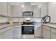 Modern kitchen with stainless steel oven and microwave, light gray cabinets, and granite countertops, offering a stylish cooking space at 3438 Briarwood Grove Dr, Ocoee, FL 34761