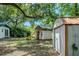 Large backyard featuring a playhouse with a slide, storage shed, and mature trees at 409 E Gulley Ave, Oakland, FL 34760