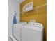 Functional laundry room with white washer, dryer, storage shelf, and ironing board for convenient chores at 441 Novi Path, Kissimmee, FL 34747