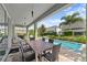 Covered patio with outdoor dining, leading to a private pool surrounded by lush landscaping at 441 Novi Path, Kissimmee, FL 34747