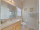 Bright bathroom featuring a single sink vanity, toilet, and shower with glass doors at 446 Summer Place Loop, Clermont, FL 34714