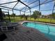 Relaxing screened-in patio with a sparkling pool, chairs and serene views of lush landscaping at 446 Summer Place Loop, Clermont, FL 34714
