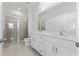 Elegant bathroom with dual sinks, large mirror, and a tiled walk-in shower at 499 Silver Palm Dr, Haines City, FL 33844