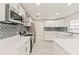 Modern kitchen with stainless appliances, white cabinets, grey backsplash and island with white countertop at 5037 Water Wheel Ct, Ocoee, FL 34761