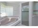 Bathroom featuring garden tub with tiled trim and glass door shower at 513 N Pine Meadow Dr, Debary, FL 32713
