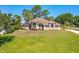 Front exterior view of this neutral-toned home with large lawn and mature landscaping at 513 N Pine Meadow Dr, Debary, FL 32713