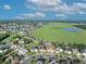 Expansive aerial view of a residential community with a large green space and pond under a bright blue sky with fluffy clouds at 5273 Sunset Canyon Dr, Kissimmee, FL 34758
