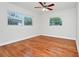 Bright, minimalist bedroom with hardwood floors, ceiling fan, and natural light from two windows at 5513 Riordan Way, Orlando, FL 32808