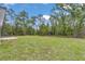 Expansive backyard featuring lush green grass, mature trees, and partial patio area at 586 Marion Oaks Trl, Ocala, FL 34473
