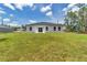 Large grassy backyard with a white home exterior and dark trim around the windows at 586 Marion Oaks Trl, Ocala, FL 34473