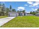 This house is a one-story home with a two-car garage, manicured lawn, black trim, and white paint at 586 Marion Oaks Trl, Ocala, FL 34473