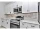 Kitchen boasts white cabinetry, stainless steel appliances, and neutral backsplash at 586 Marion Oaks Trl, Ocala, FL 34473