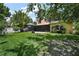 Spacious backyard with lush green grass, mature trees, and screened-in lanai at 612 Heron Bay Dr, Orlando, FL 32825