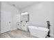 This primary bathroom has a soaking tub, double sinks, and a modern light fixture at 6691 Sw 151Sr Loop, Ocala, FL 34473