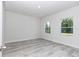 Bedroom featuring light gray wood floors, two windows, and white trim at 6691 Sw 151Sr Loop, Ocala, FL 34473